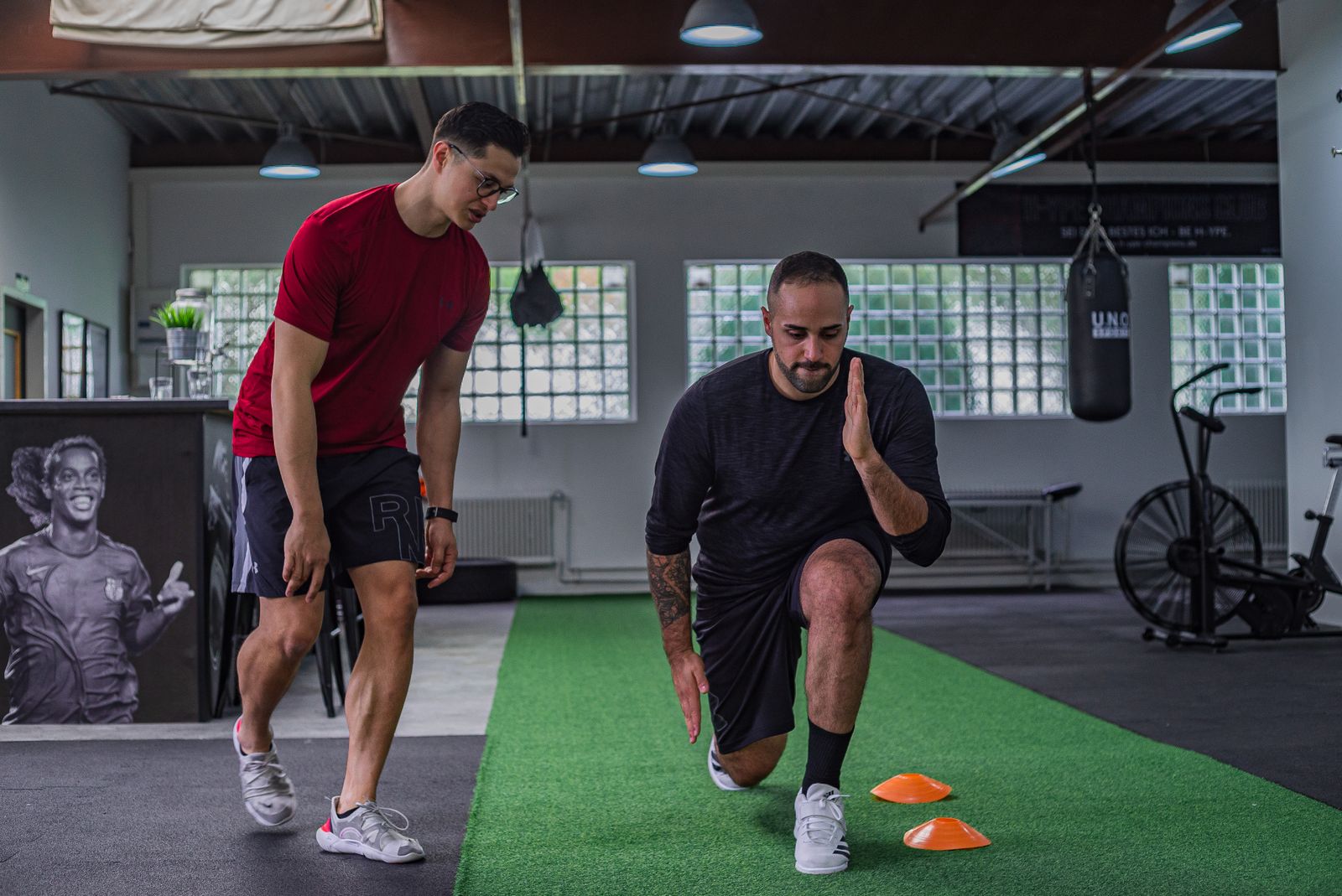 Un entraîneur personnel guide un client à travers une routine de fitness à l'intérieur.